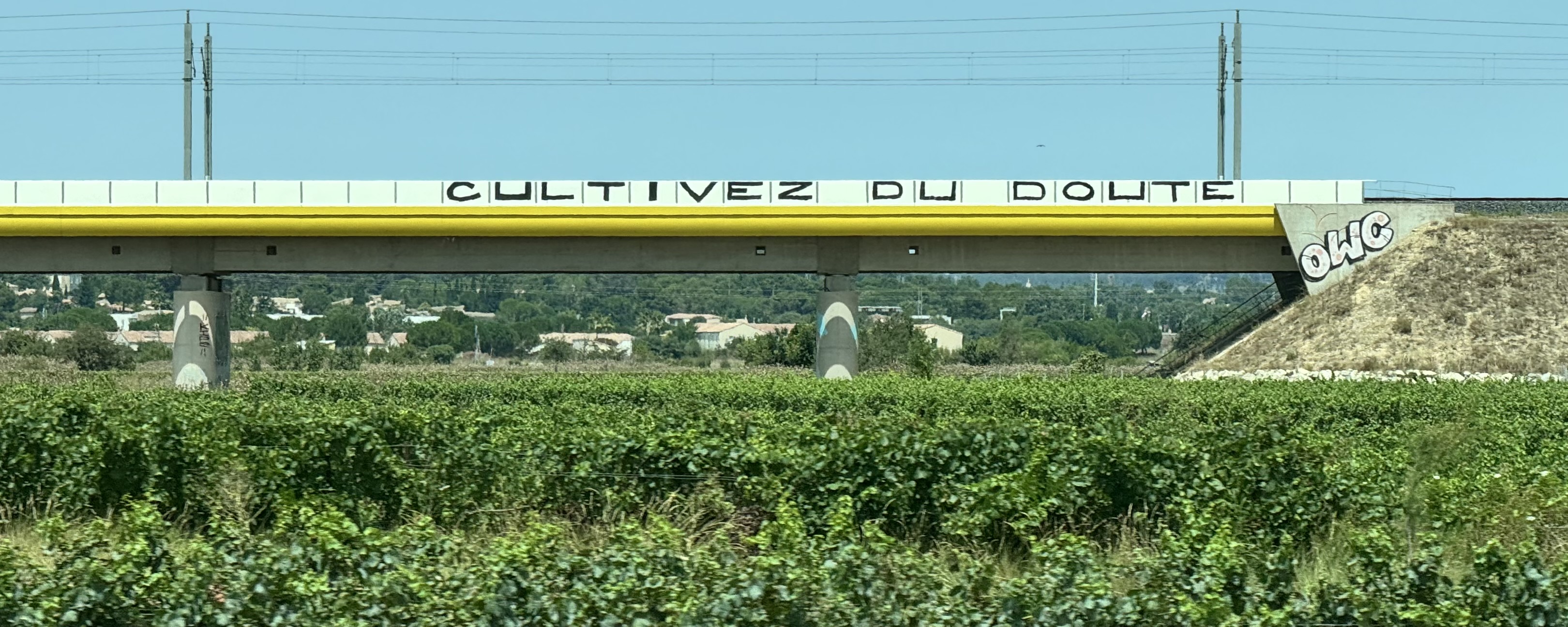 French train bridge with "cultivez du doubt" written on it in graffiti